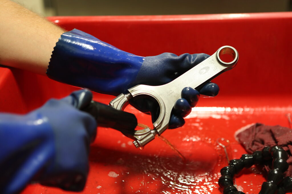 connecting rod being cleaned in a parts washer